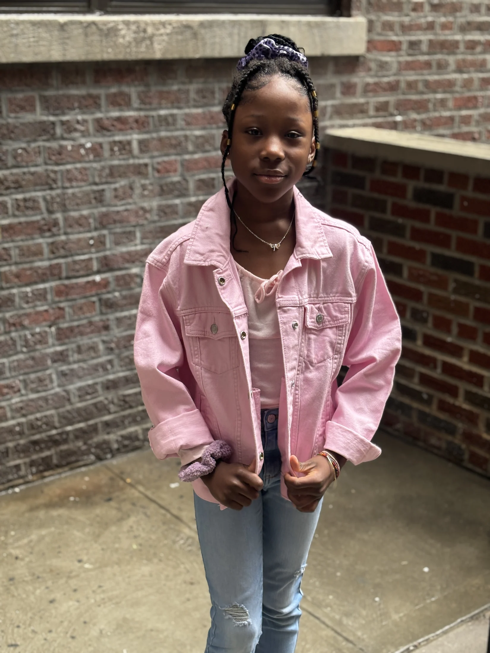Avi wearing a pink jacket and jeans