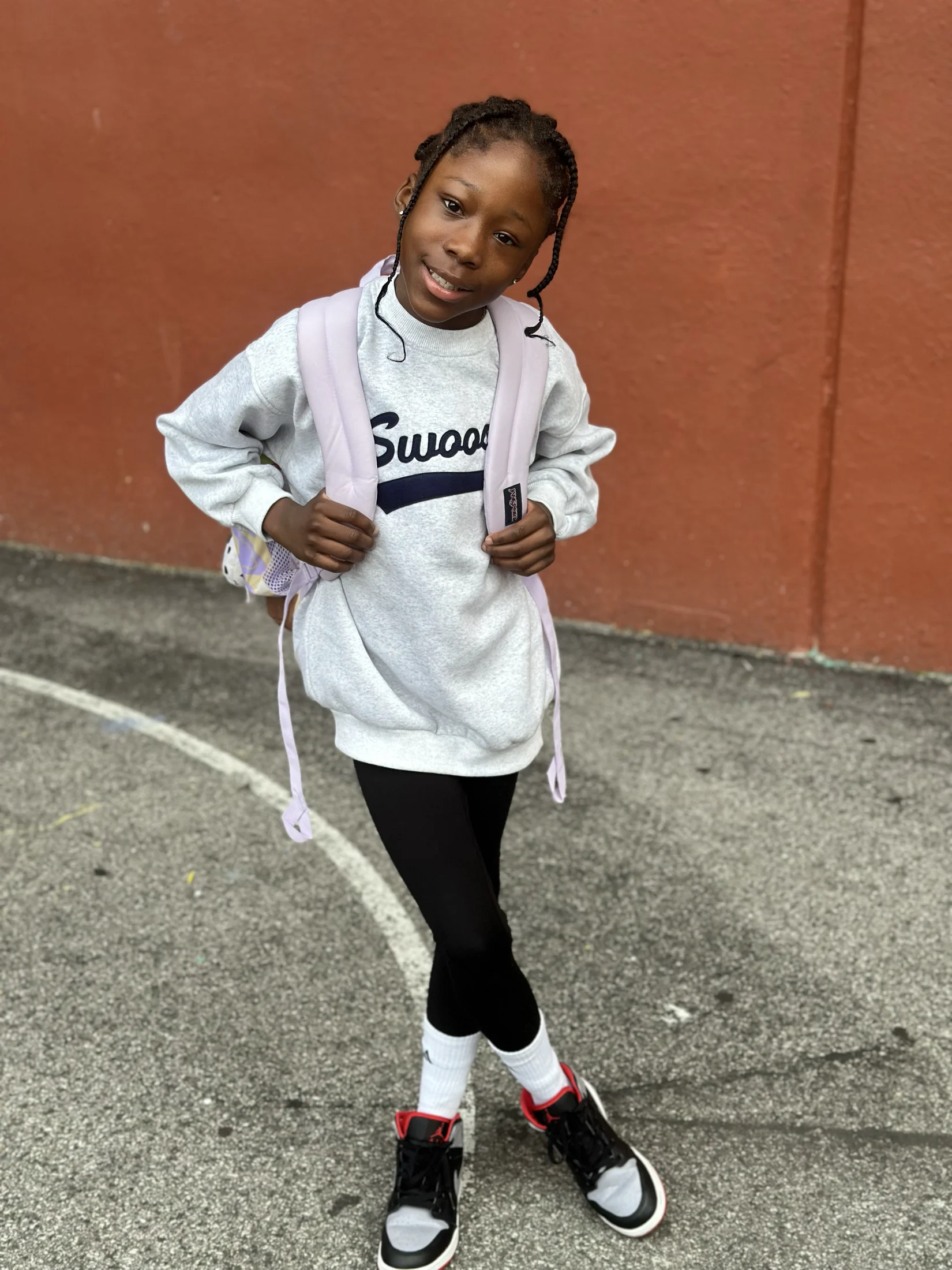 Avi posing outdoors in a white Swag sweatshirt
